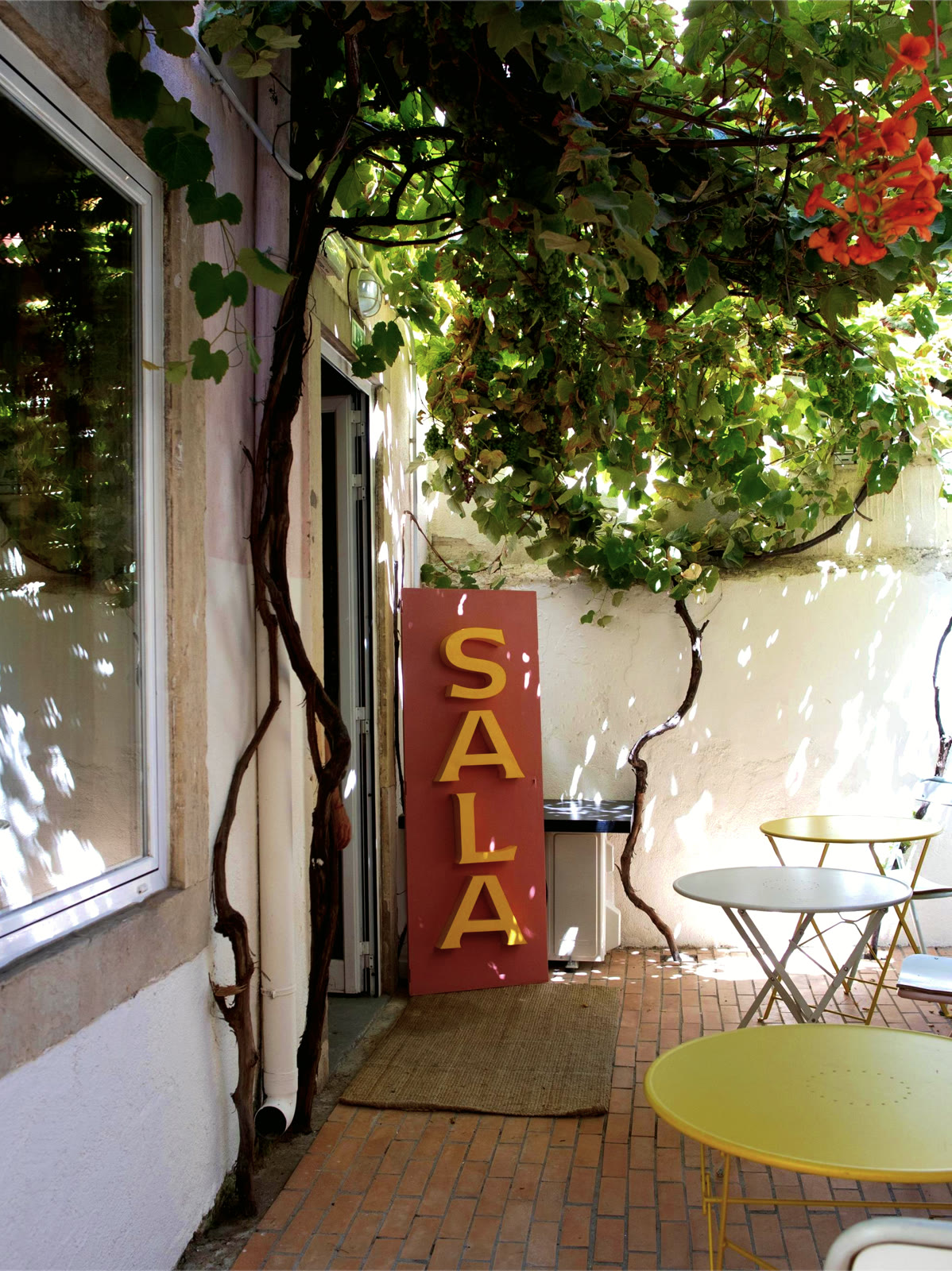 The patio under the vine, with the A SALA sign